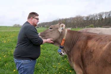 Landwirt Benedikt Reuter mit einer Kuh auf der Weide