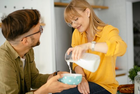 Frau gießt Mann Milch in eine Schüssel