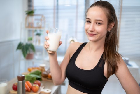 Frau nach dem Training mit einem Glas Milch in der Hand