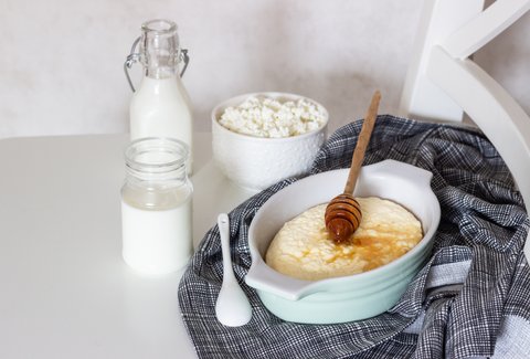 Milchflasche, Joghurtglas, körniger Frischkäse und Milchreis in Auflaufform